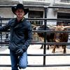 Professional bull rider Douglas Duncan standing outside the New York Stock Exchange with a couple of bulls.